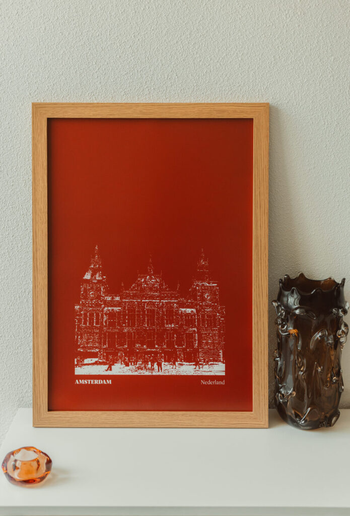 Stillorange poster Amsterdam in interieur Ingelijste Stillorange-poster van Amsterdam Centraal op een dressoir met glazen vaas
